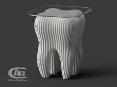 a tooth shaped object sitting on top of a gray surface with the words ab design above it