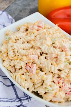 a white bowl filled with macaroni salad next to tomatoes