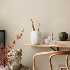 there are two vases on the table with some flowers in them and one is sitting next to a statue