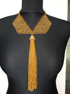 This unique gold tassel pendant necklace is a unique and luxurious piece of jewelry for any special occasion. It is made entirely of Czech beads, and in the hat of the tassel I have swapped several Swarovski crystals. The buckle is made is from the same beads . This is the perfect gift for yourself or a loved one who values uniqueness and class. Elegant Gold Beaded Necklaces For Gifts, Elegant Gold Beaded Necklaces For Parties, Elegant Party Beaded Necklaces With Gold Beads, Elegant Party Gold Beaded Necklaces, Elegant Gold Chain Necklace With Beads, Elegant Gold Beaded Chain Necklace For Party, Handmade Luxury Gold Beaded Necklaces, Gold Round Beaded Necklaces For Party, Party Tassel Dangle Necklaces