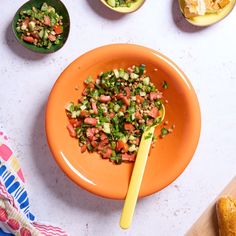 an orange bowl filled with chopped vegetables next to bowls of other food on a table