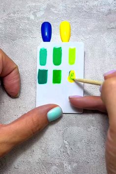 a person is holding a match card with different colors on it and a toothpick in their hand