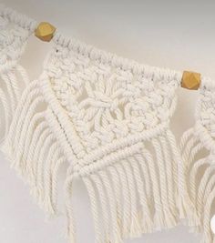 there is a white crocheted wall hanging with gold beads on the top and bottom