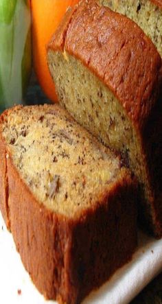 sliced loaf of banana bread sitting on top of a cutting board next to an orange