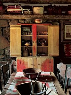 an old fashioned kitchen table with chairs and cupboards