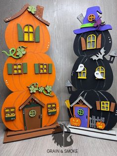 two halloween decorations made to look like pumpkins and houses with bats on them, sitting next to each other