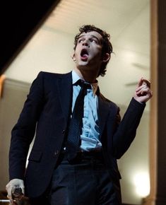 a man in a suit and tie making a funny face with his mouth wide open