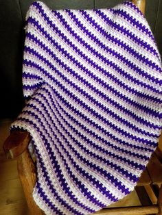 a purple and white crocheted blanket sitting on top of a wooden rocking chair