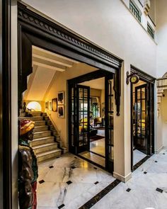 an entry way with marble flooring and black glass doors leading to the second story