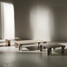 three wooden benches sitting next to each other in a room with sunlight streaming through the windows