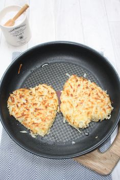 two pieces of food cooking in a frying pan next to a wooden spatula