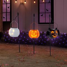 three halloween pumpkin shaped lights in front of a house