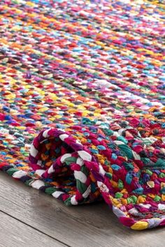 a multicolored rug is laying on top of a wooden floor and it's end rolled up