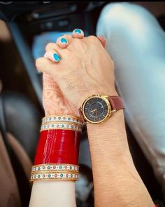 two people holding hands while sitting in a car with their wrist watches on the other hand