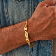 a man wearing a gold bracelet with the word trust engraved on it's side