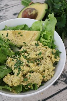 a white bowl filled with lettuce and avocado