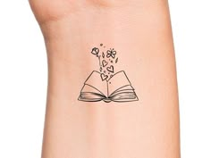 an open book with hearts coming out of it tattoo on the left side of the arm