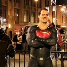 two men dressed as batman and supermangirls standing in front of a building at night