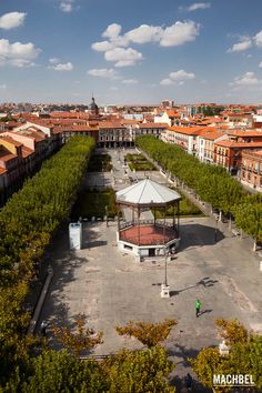 an aerial view of a city with lots of trees in the foreground and a gazebo surrounded by buildings