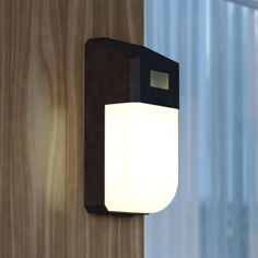 a light that is on the side of a wall next to a wooden paneled wall