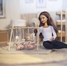 a doll sits on the floor next to a baby's cradle with dolls in it