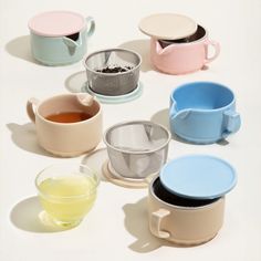 there are many cups and saucers on the table with one cup full of tea