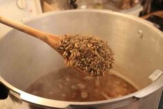 a wooden spoon full of some kind of food in a pot on the stove top