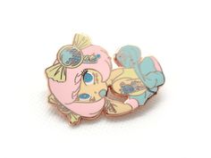 two pink and blue pin badges sitting on top of each other