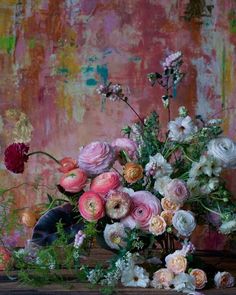 a vase filled with lots of flowers on top of a wooden table next to a wall