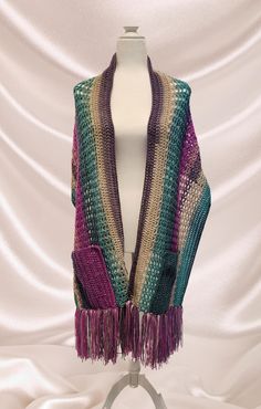 This hand knit pocket scarf is perfect when it's a little chilly, but you don't want to wear a coat. It is made in a beautiful multicolored pattern which includes shades of green, purple, pink, and cream. It will go perfectly with your favorite jeans, and the fringe at the bottom gives it a distinct boho flair! The yarn is composed of 30% wool and 70% acrylic. The wool content helps to keep you warm without adding a lot of weight. Crochet Pocket Scarf, Crochet Pocket, Pocket Scarf, Knit Pocket, Hazel Green, Pocket Scarves, Boho Crochet, Favorite Jeans, Shades Of Green