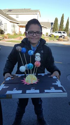 a young boy is holding up a table made out of magnets and paper balls