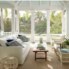 a living room filled with white furniture and lots of glass doors leading to an outside deck