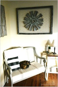 a cat laying on top of a white couch in front of a wall mounted clock