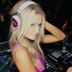 a woman with headphones is playing music on a dj's mixer at a party