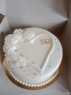 a heart shaped cake in a box with white frosting and gold sprinkles