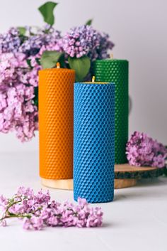 two colorful candles sitting next to purple flowers