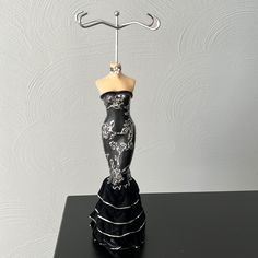 a black and white dress with a hanger on it's head is sitting on a table