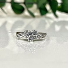 a close up of a ring on a white surface with flowers in the back ground