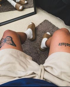 a person with tattoos on their legs sitting in front of a mirror