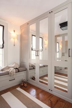 a bedroom with mirrored closet doors and wooden flooring on the side, along with white walls