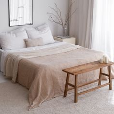 a bedroom with white walls and carpeted flooring, a large bed covered in beige linens