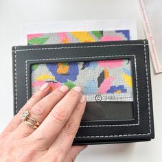 a woman is stitching a colorful pattern on a piece of fabric with her hands