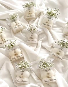 wedding favors are arranged on a white satin sheet with baby's breath in the center