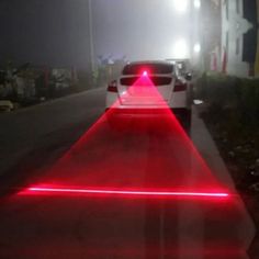 a car driving down a street with red laser lights on it's taillights