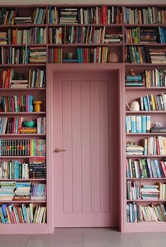 a pink bookcase filled with lots of books next to a wooden door and window