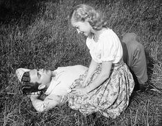 an old black and white photo of a woman laying on the ground next to a man