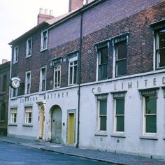 an old brick building on the corner of a street with boarded up windows and doors