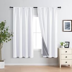 a living room with white curtains and a potted plant