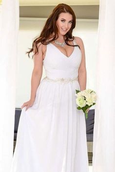 a woman wearing a white dress standing in front of a window with her hands on her hips