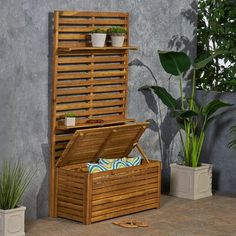 a wooden storage box sitting next to a potted plant